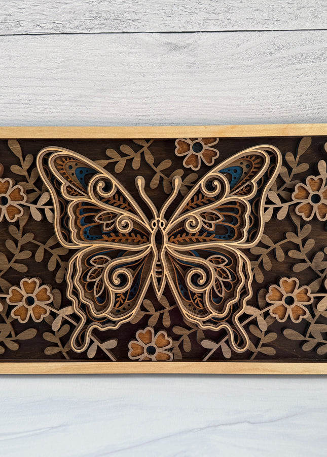 Butterfly layered wood wall art front view showing intricate mandala wing detail and full floral border in natural maple plywood with dark background