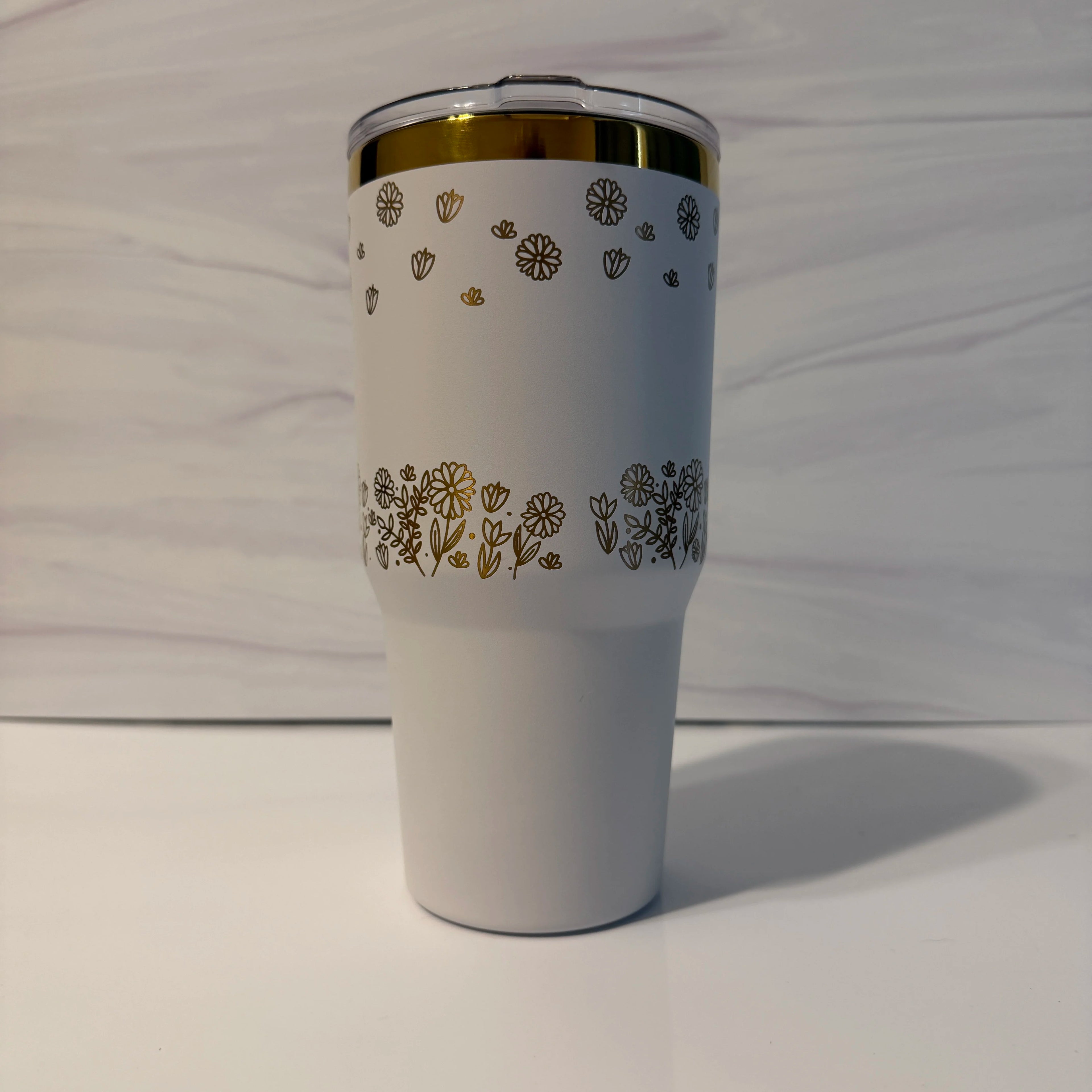 Alt text: Back view of white and gold electroplated laser-engraved tumbler showing full floral meadow wrap design by Cactus Air Designs