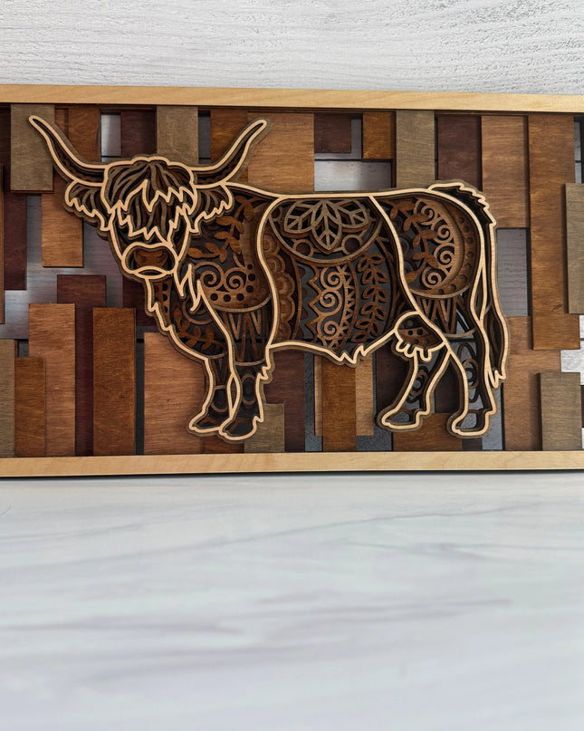 Front view of a 3D layered Highland Cow wall art featuring five intricate laser-cut wood layers and warm golden oak to red mahogany stained bar background