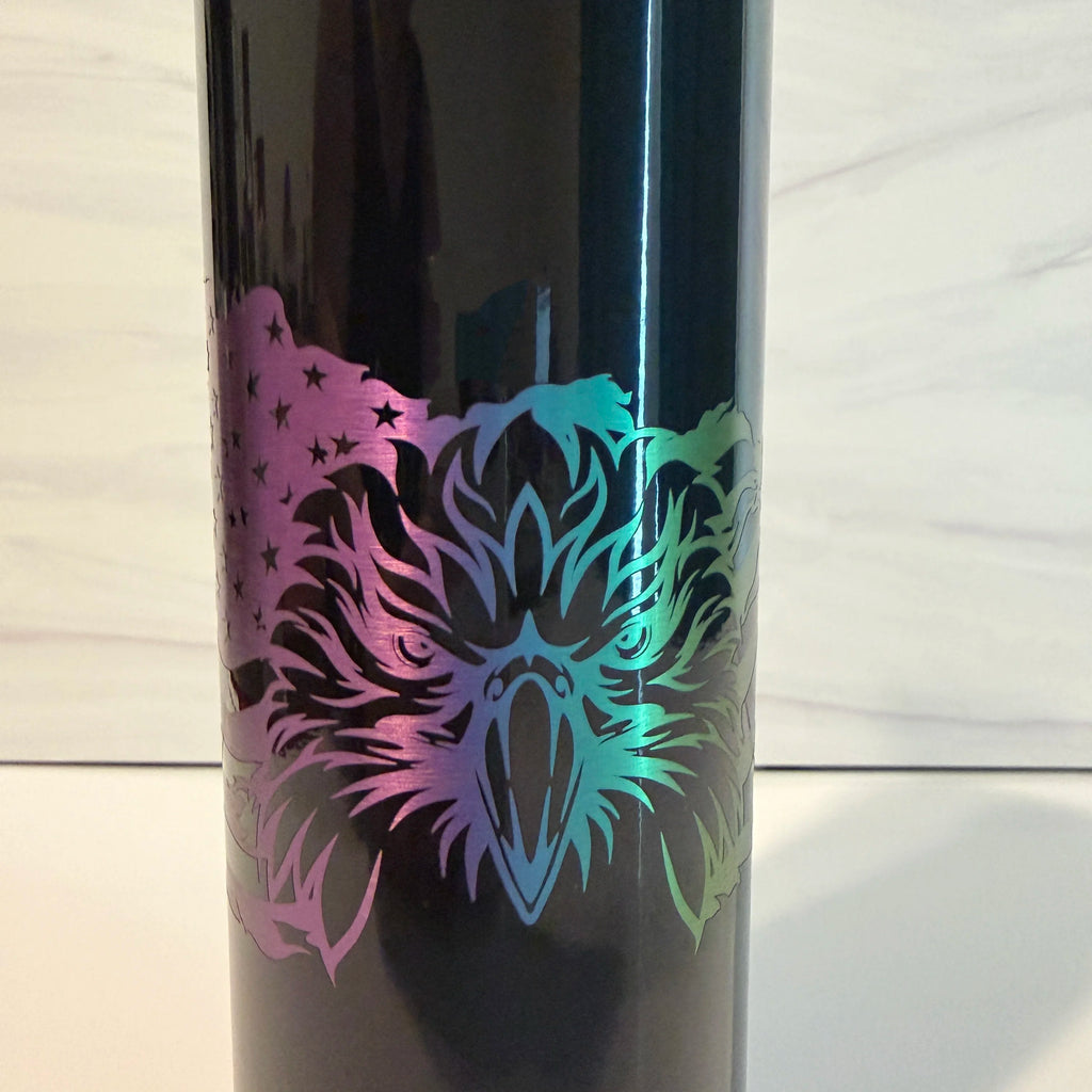 Closeup of laser engraved bald eagle face with rainbow metallic electroplate on black tumbler, purple teal and green color shift visible
