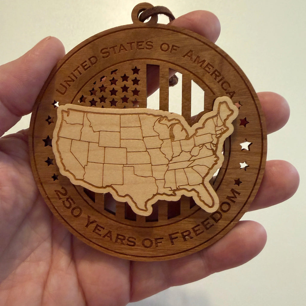 Hand holding USA 250th Anniversary USA Map wood ornament showing actual size approximately 3.5 inches handcrafted by Cactus Air Designs Arizona