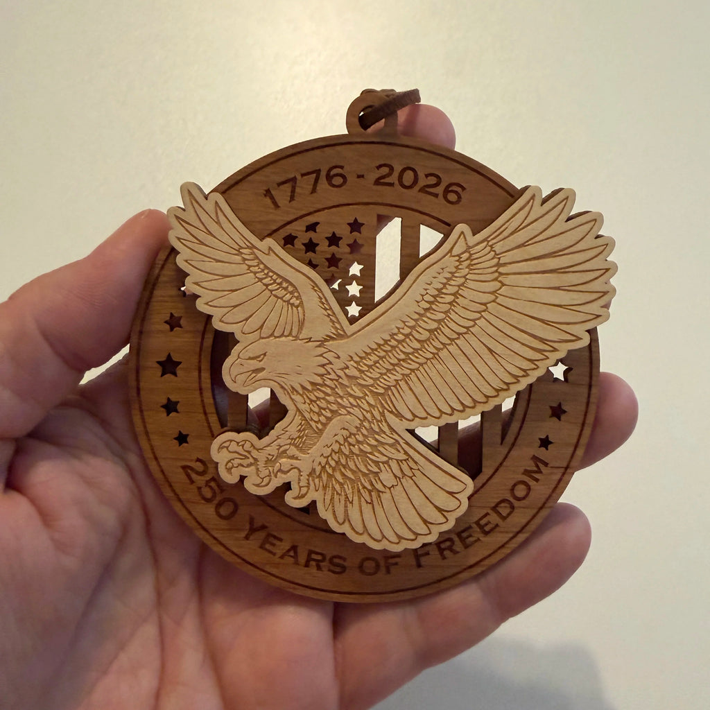 Hand holding USA 250th Anniversary Bald Eagle wood ornament showing actual size approximately 3.5 inches handcrafted by Cactus Air Designs Arizona