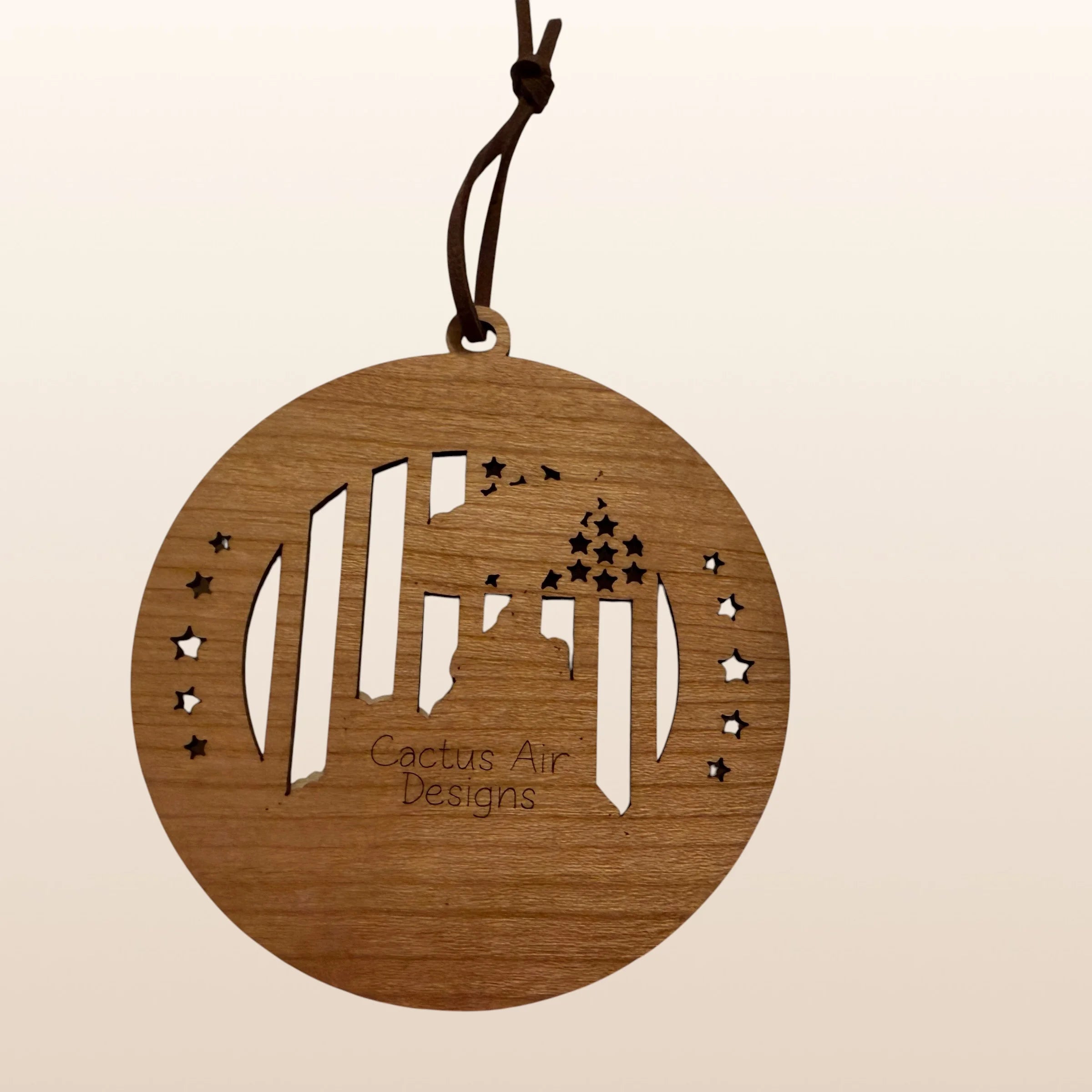 Back of USA 250th Anniversary Flag Raising ornament showing Cactus Air Designs maker's mark on Premium Cherry plywood with leather cord hanger