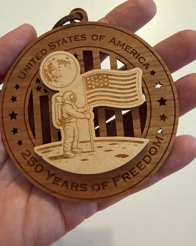 Hand holding USA 250th Anniversary Moon Landing wood ornament showing actual size approximately 3.5 inches handcrafted by Cactus Air Designs Arizona