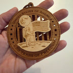 Hand holding USA 250th Anniversary Moon Landing wood ornament showing actual size approximately 3.5 inches handcrafted by Cactus Air Designs Arizona