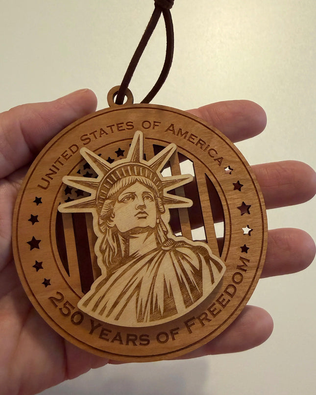 Hand holding USA 250th Anniversary Statue of Liberty wood ornament showing actual size approximately 3.5 inches handcrafted by Cactus Air Designs Arizona