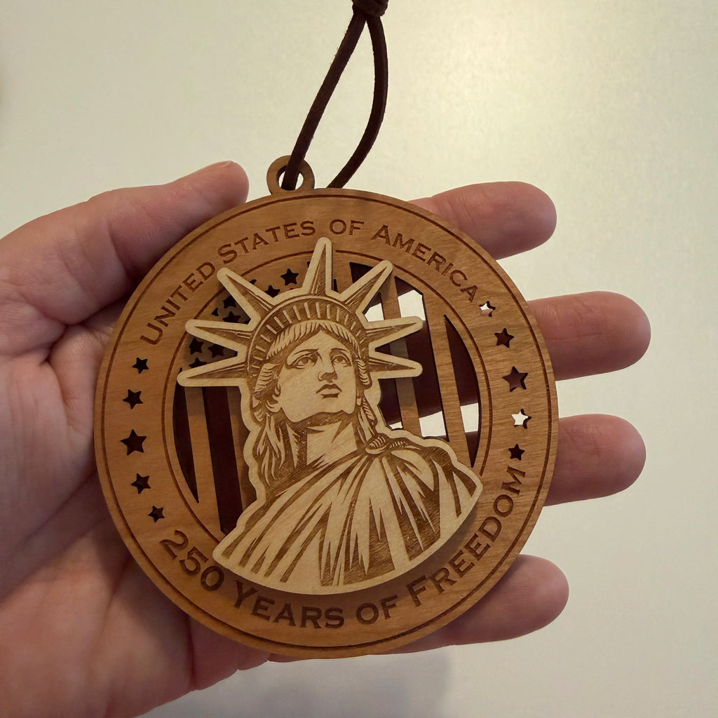 Hand holding USA 250th Anniversary Statue of Liberty wood ornament showing actual size approximately 3.5 inches handcrafted by Cactus Air Designs Arizona