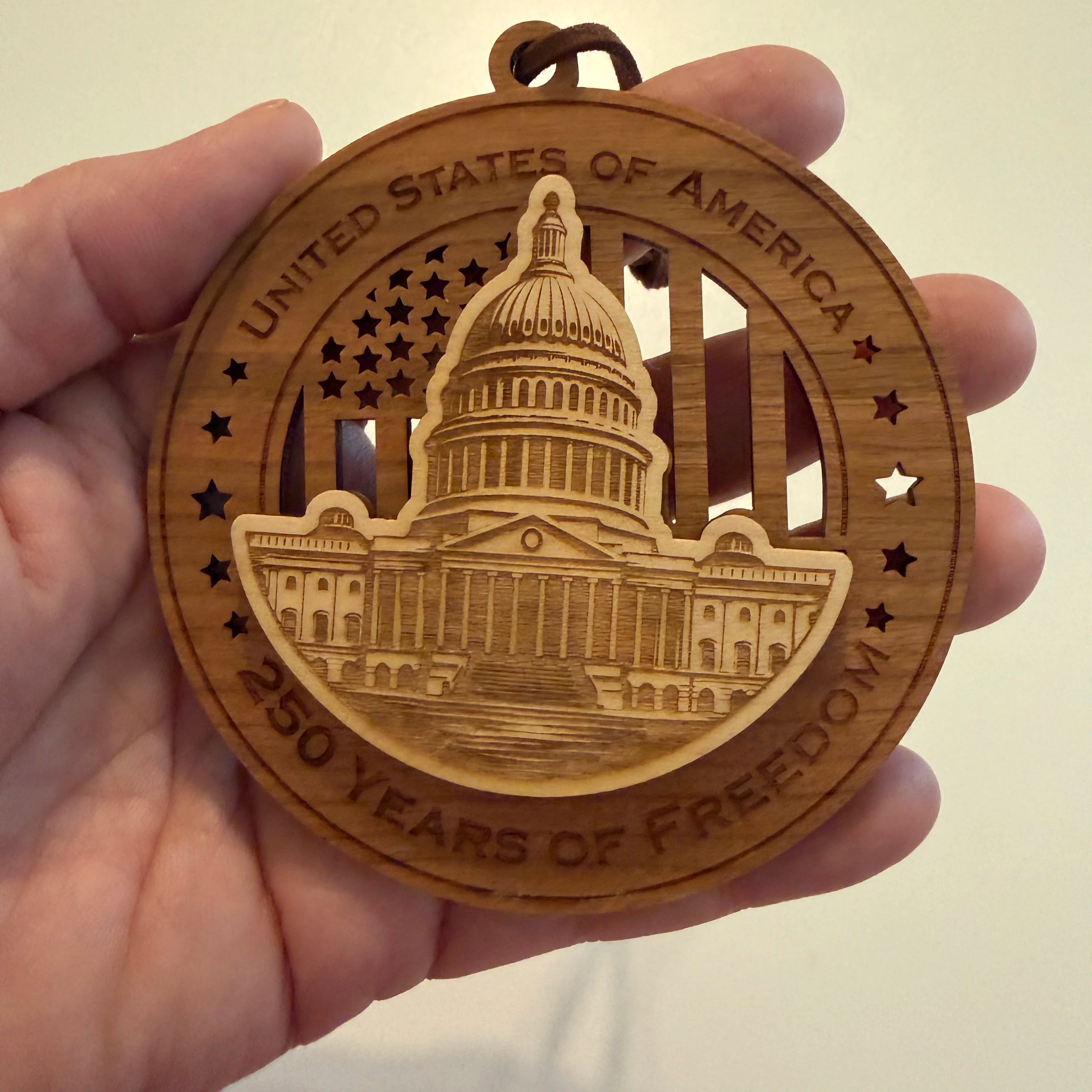 Hand holding USA 250th Anniversary US Capitol wood ornament showing actual size approximately 3.5 inches handcrafted by Cactus Air Designs Arizona