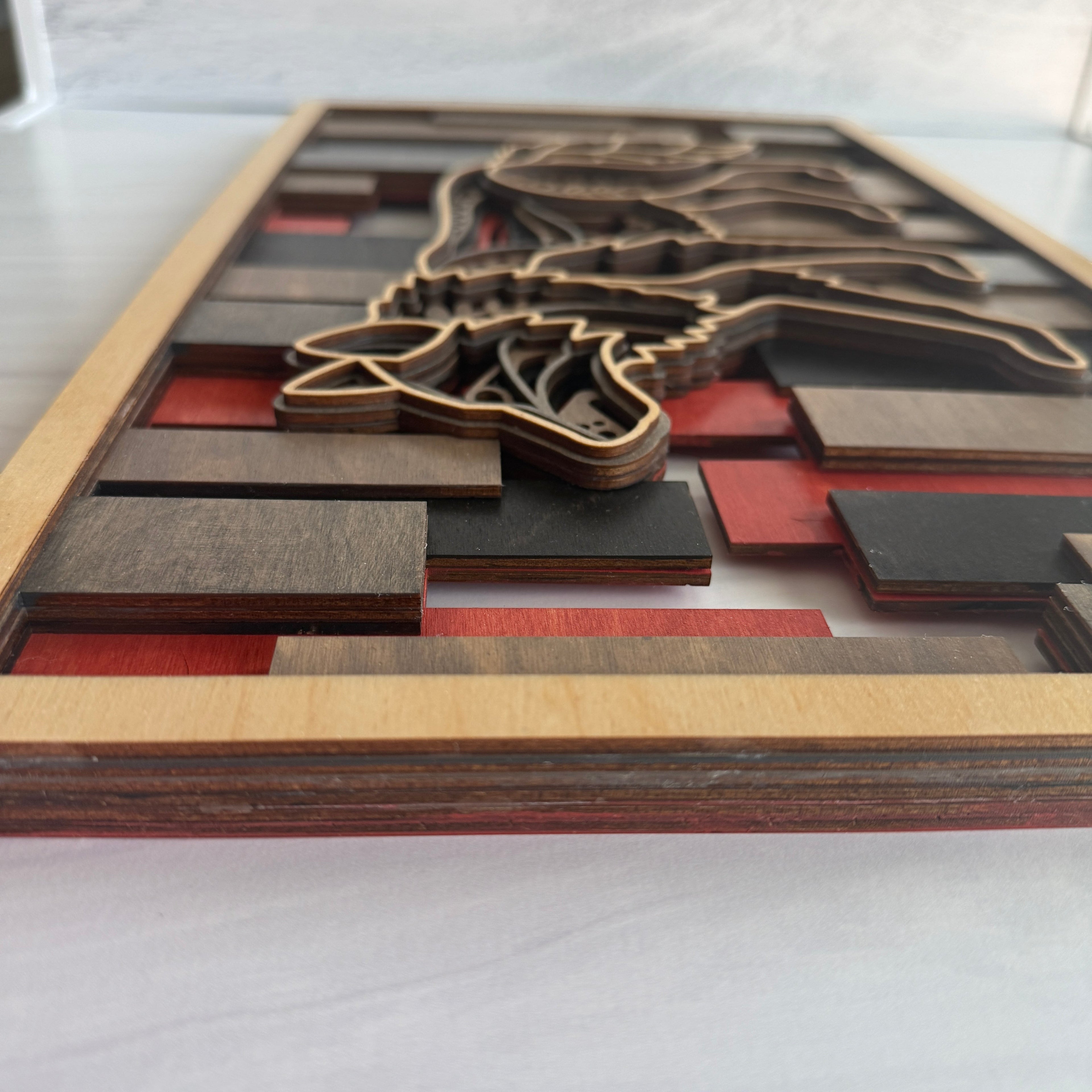 Short side view of 3D wolf wall art showing the depth of five individual wood layers and the textured 'mandala' style engravings on the wolf silhouette