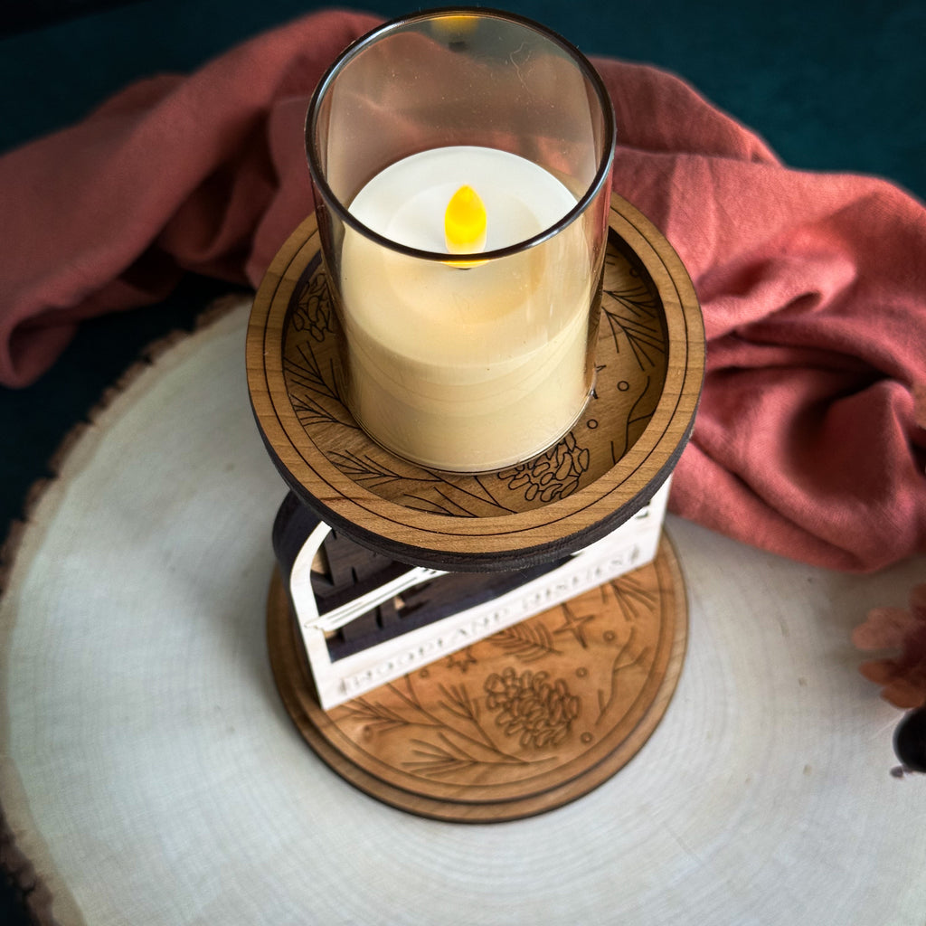 Candle in a wooden holder with intricate designs on a rustic surface.