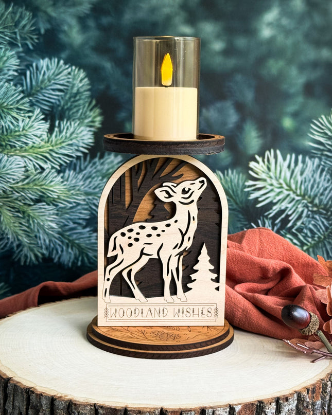 Decorative candle holder with fawn design on a wooden base against a green foliage background