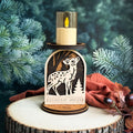 Decorative candle holder with fawn design on a wooden base against a green foliage background