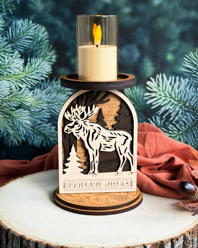 Wooden candle holder with moose design and 'Woodland Wishes' text, set against a natural background.