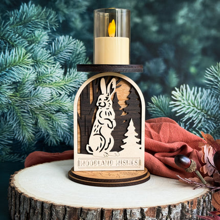 Wooden candle holder with rabbit design on a tree stump against a forest background