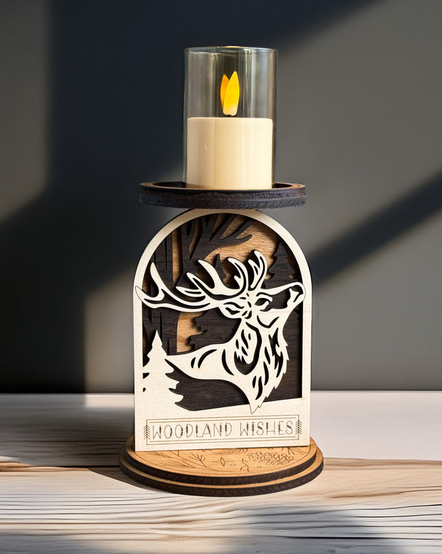 Decorative candle holder with a cut-out design of a deer and the text 'Woodland Wishes' on a wooden surface.