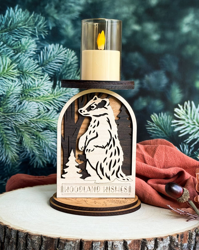 Wooden candle holder with weasel design and 'Woodland Wishes' text, against a green foliage background.