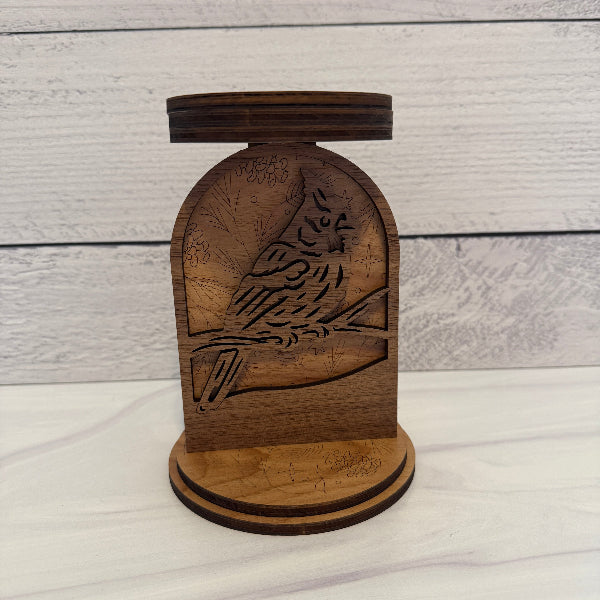 Wooden candle holder with bird design on a wooden background