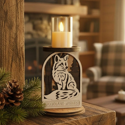 Layered wood woodland fox candle holder with LED candle lit on a rustic wood cabin surface with pine branches and pine cones