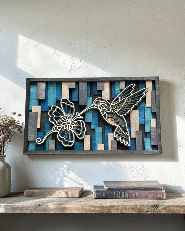 Hummingbird layered wood wall art leaning on rustic wood console with ceramic vase of dried flowers and vintage books