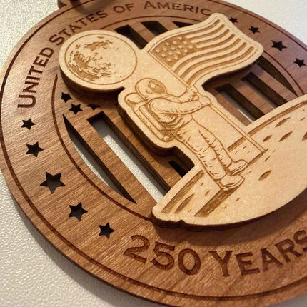 Close Up detail of laser cut Astronaut with American flag and moon on USA 250 Years of Freedom wood ornament showing maple and cherry layers
