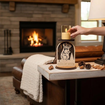 Hand placing LED candle into woodland mouse layered plywood candle holder on a side table near a lit fireplace