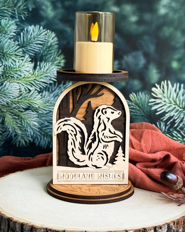 Layered wood woodland skunk candle holder with LED candle lit, displayed on a wood slice with pine branches in background