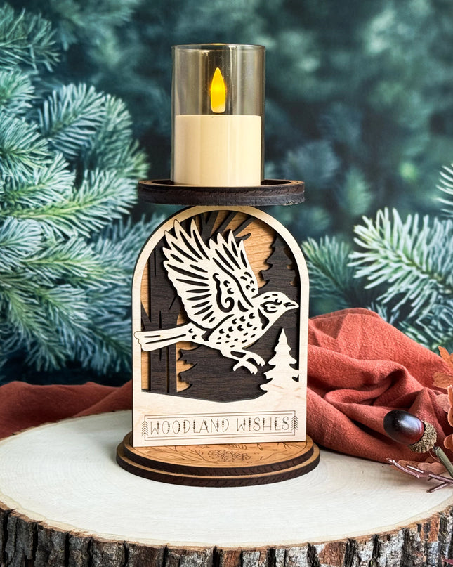 Layered wood woodland sparrow candle holder with LED candle lit on a rustic stone cabin mantel with pine branches and pine cones