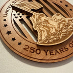 Close up detail of laser engraving on USA 250th Anniversary 
Flag Raising wood ornament showing Premium Cherry plywood and Maple plywood layers
