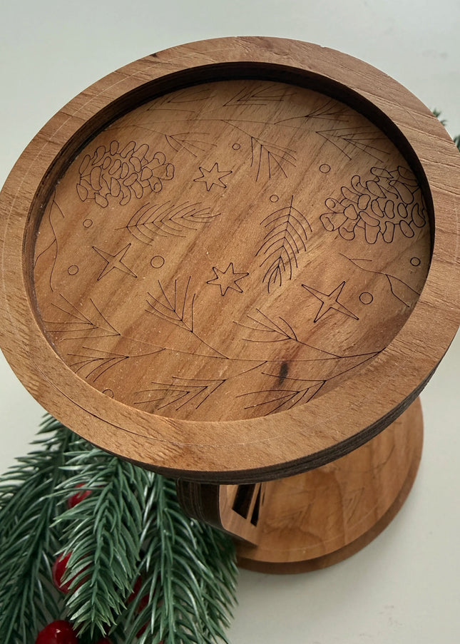 Top-down view of engraved botanical candle platform showing clean hidden tab finish, pine cone and star pattern