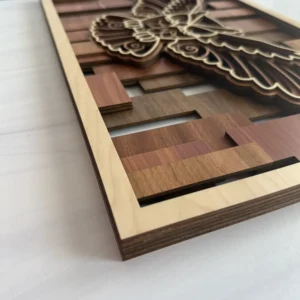 Corner angle of owl layered wall art showing stacked wood species layers and mosaic slat background with natural maple frame edge