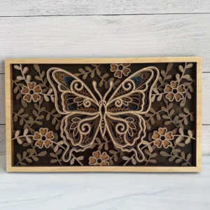 Front view of the layered butterfly wood wall art laying flat on a white wood panel background.