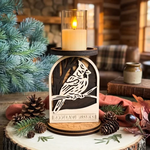 Layered wood cardinal candle holder with Woodland Wishes engraving on a wood slice with pine branches and pinecones, stone fireplace glowing with warm golden light and stacked antique books in background