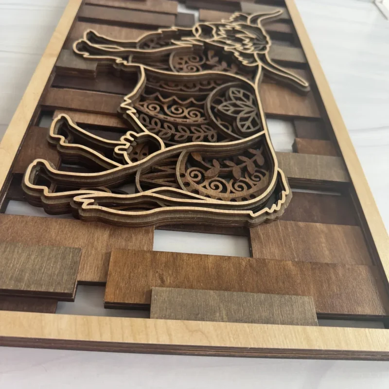 Angled view showing layer depth and earthy mosaic slat background on layered highland cow wall art