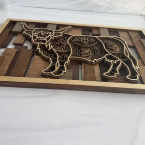 Close-up of mandala engravings and stained wood layer construction on highland cow wall art