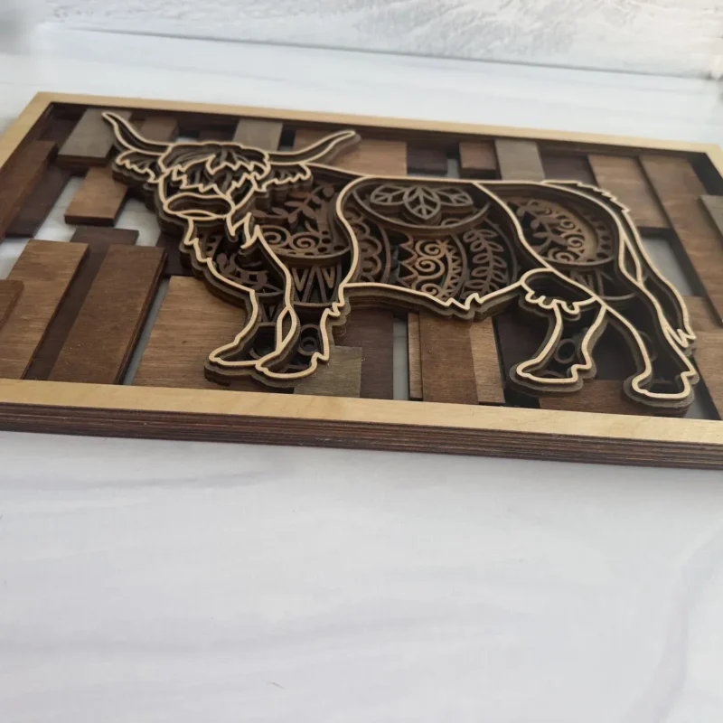 Close-up of mandala engravings and stained wood layer construction on highland cow wall art