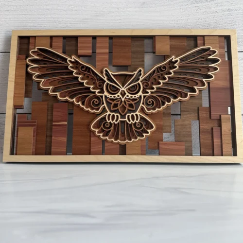 Owl layered wall art front view with wings spread over mosaic wood species background in natural maple frame
