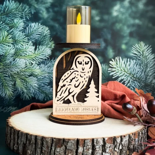 Owl woodland candle holder on a wood slice with deep teal pine background and rust cloth with dark fall berries and autumn leaves