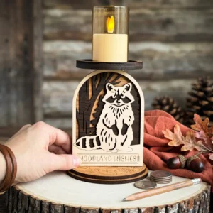 Hand with leather bracelet lifting layered maple walnut and cherry raccoon woodland candle holder from a wood slice on weathered wood planks with large pinecones and fall oak leaves