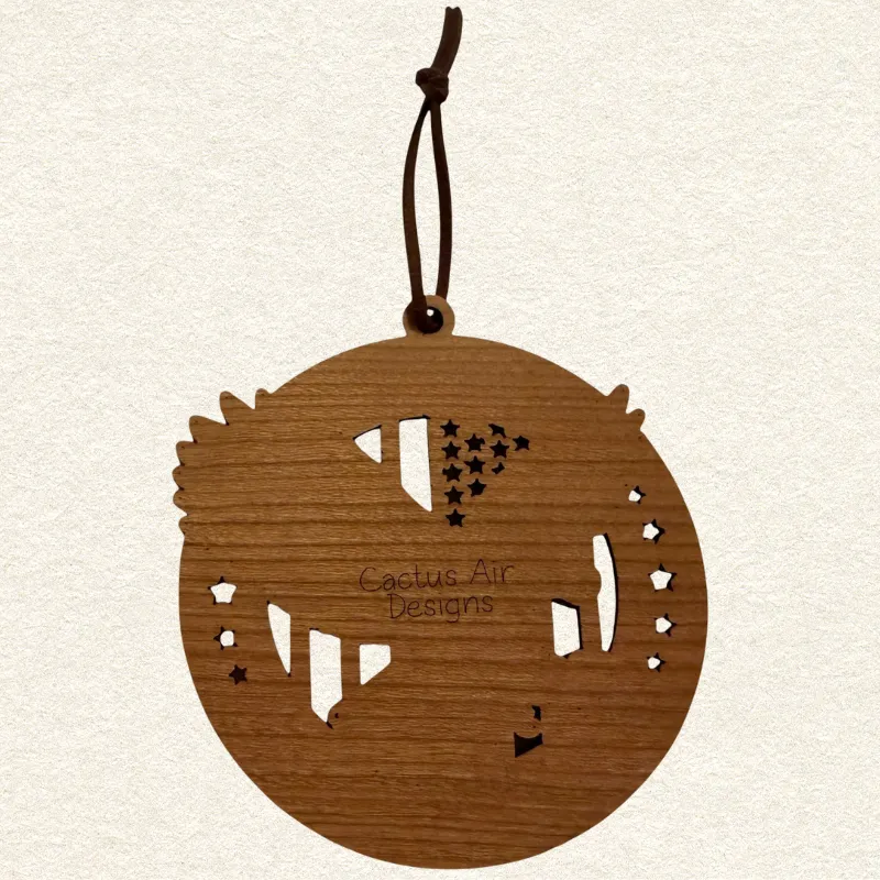 Back of the round wooden ornament showing the natural wood grain, an attached brown hanging cord, and “Cactus Air Designs” laser engraved in a delicate single-line font.