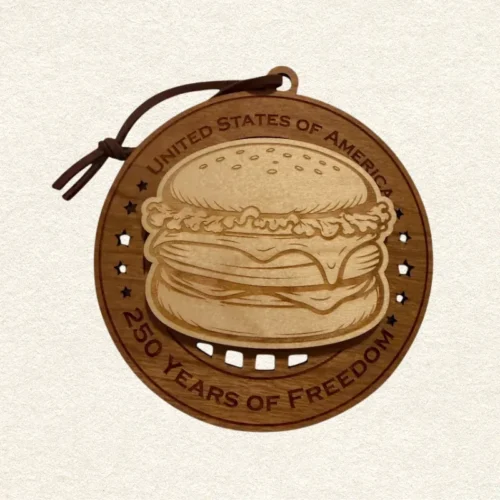 usa-250-cheeseburger-wood-ornament-front Round two-layer wooden ornament with "United States of America" and "250 Years of Freedom" engraved on the border, featuring a laser-cut flag with cut-through stripes and star field, topped with a detailed cheeseburger, hung on a brown cord