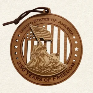 Round two-tone wood ornament depicting the Iwo Jima flag raising over stars and stripes, engraved “United States of America” and “250 Years of Freedom" and hung on a brown cord