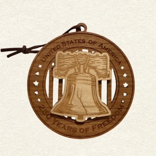 Round two-layer wooden ornament with "United States of America" and "250 Years of Freedom" engraved on the border, featuring a laser-cut flag with cut-through stripes and star field, topped with a detailed Liberty Bell and its crack on it, hung on a brown leather cord
