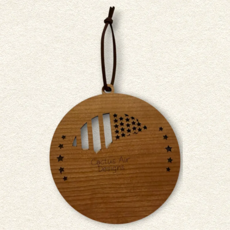Back of the round wooden ornament showing the natural wood grain, an attached brown hanging cord, and “Cactus Air Designs” laser engraved in a delicate single-line font.