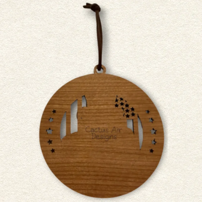 Back of the round wooden ornament showing the natural wood grain, an attached brown hanging cord, and “Cactus Air Designs” laser engraved in a delicate single-line font.