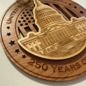 Close-up detail of a layered wooden ornament showing a raised U.S. Capitol with finely laser-engraved dome, columns, windows, steps, and architectural details over a cut-through American flag background.