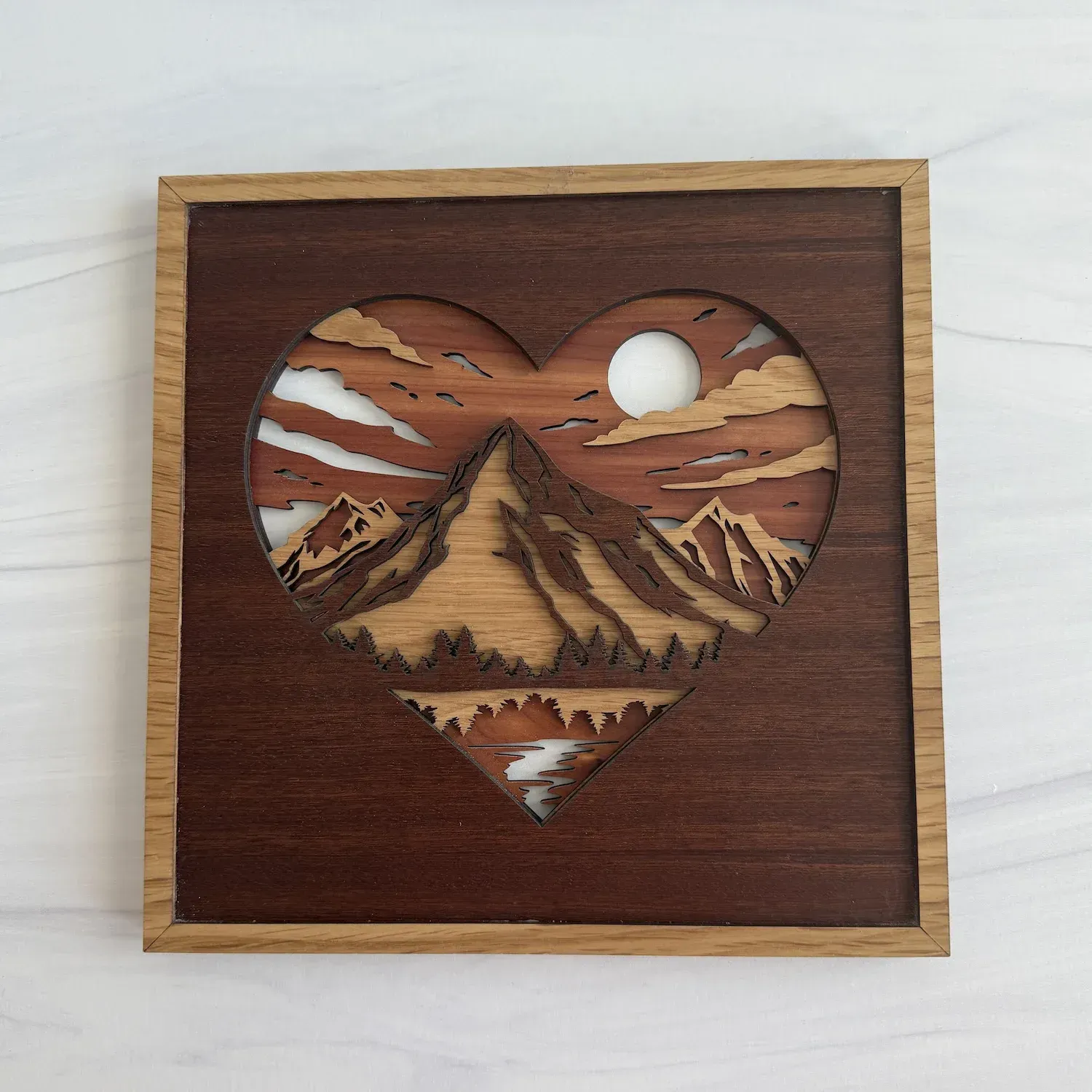 Mountain heart wood wall art with peaks, evergreens, and cherry frame